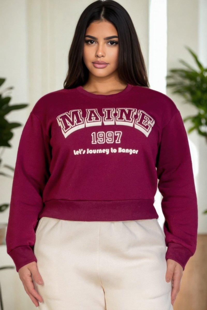 Woman wearing a maroon sweatshirt with 'MAINE 1997' text, standing indoors.