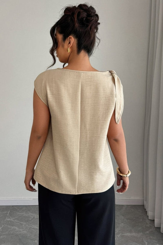 Woman wearing a beige top with a plain background