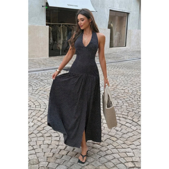 Woman in a black patterned dress walking on a cobblestone street.