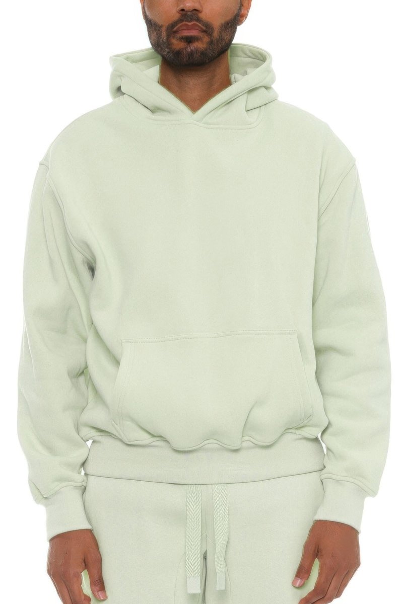 Man wearing a light green hoodie and pants on a white background