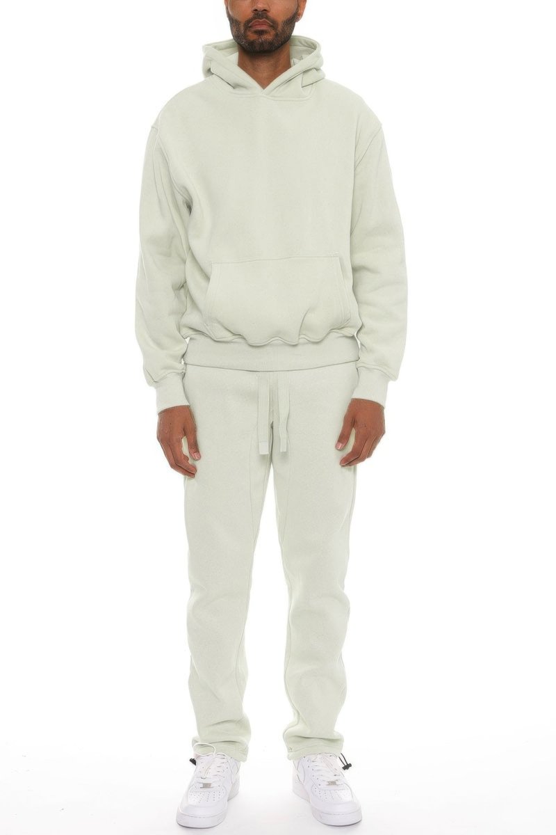 Person wearing a beige hoodie and pants set on a white background