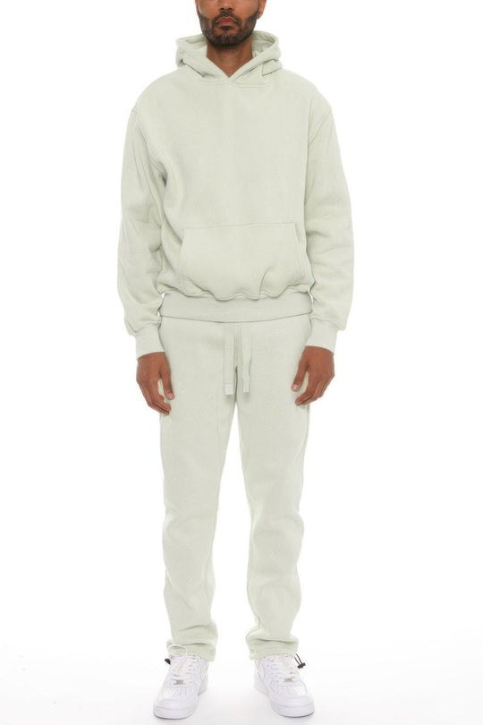 Person wearing a beige hoodie and pants set on a white background