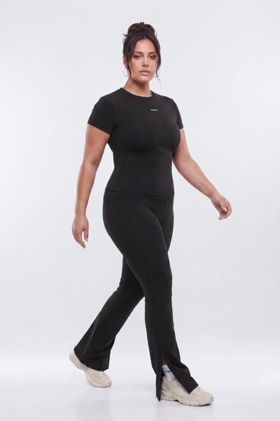 Woman wearing a black outfit with a visible brand logo on a white background
