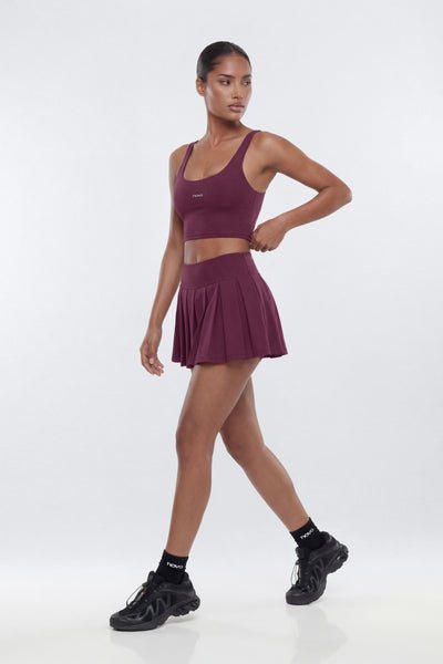 Woman wearing a maroon athletic outfit on a white background