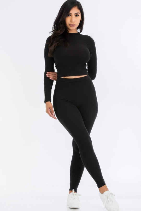 Woman wearing a black long-sleeve top and leggings on a white background