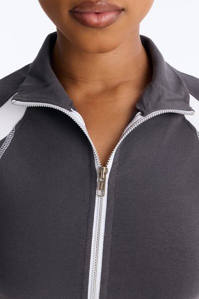 Close-up of a person wearing a gray and white zip-up sweatshirt.