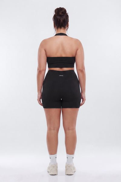 Person wearing a black strapless top and high-waisted shorts on a white background