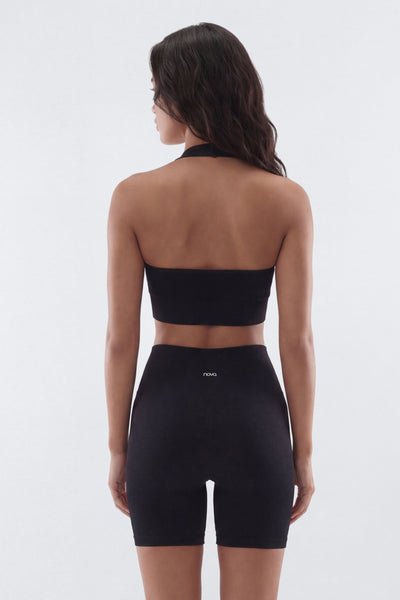 Woman wearing a black sports bra and shorts set on a white background