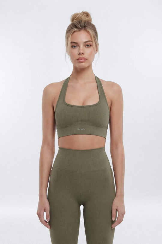 Woman wearing a green sports bra and leggings set on a white background