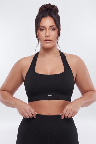 Woman wearing a black sports bra with a visible brand logo on a white background