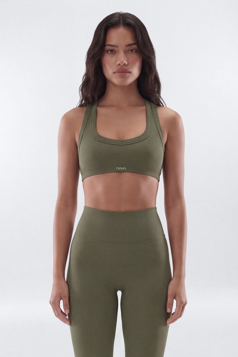 Woman wearing a green sports bra and leggings set on a white background