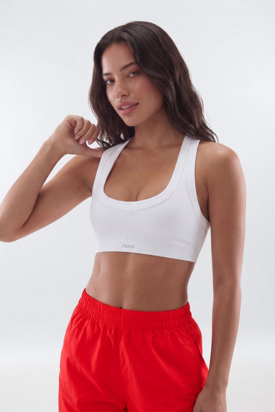 Woman wearing a white sports bra and red shorts on a white background