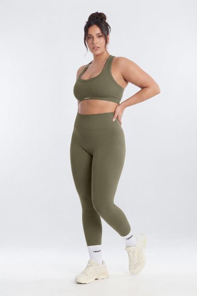 Woman wearing a green sports bra and leggings set on a white background