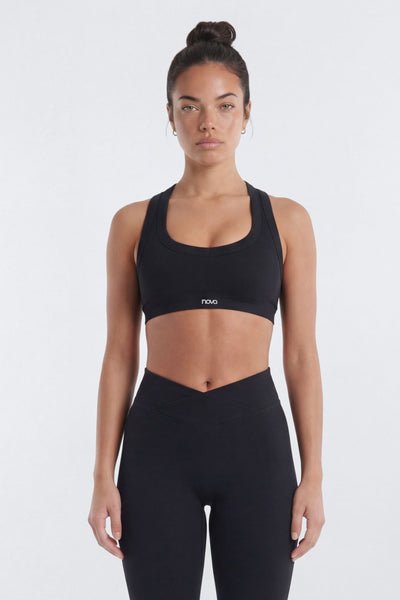 Woman wearing a black sports bra and leggings on a white background