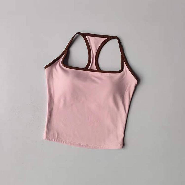 A light pink racerback tank top with dark brown trim, laid flat on a neutral gray background.
