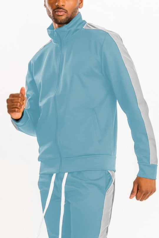 Man wearing a light blue tracksuit with white stripes on a white background