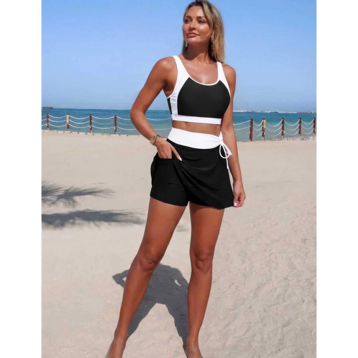 Woman in black and white athletic outfit standing on a beach.