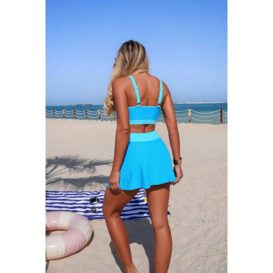 Woman in a blue swimsuit standing on a beach with ocean view