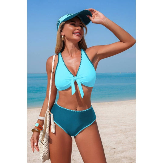 Woman in a blue bikini and visor standing on a beach.