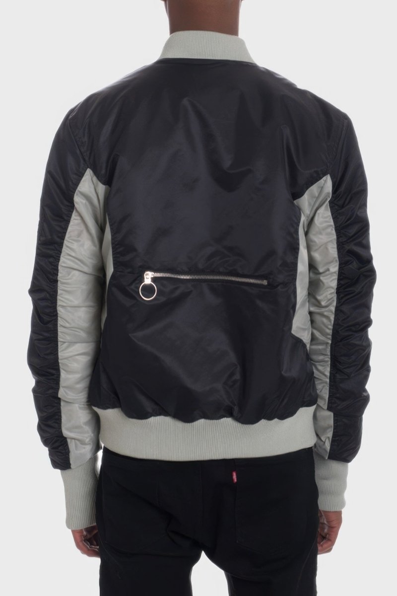 Person wearing a black and gray bomber jacket on a white background
