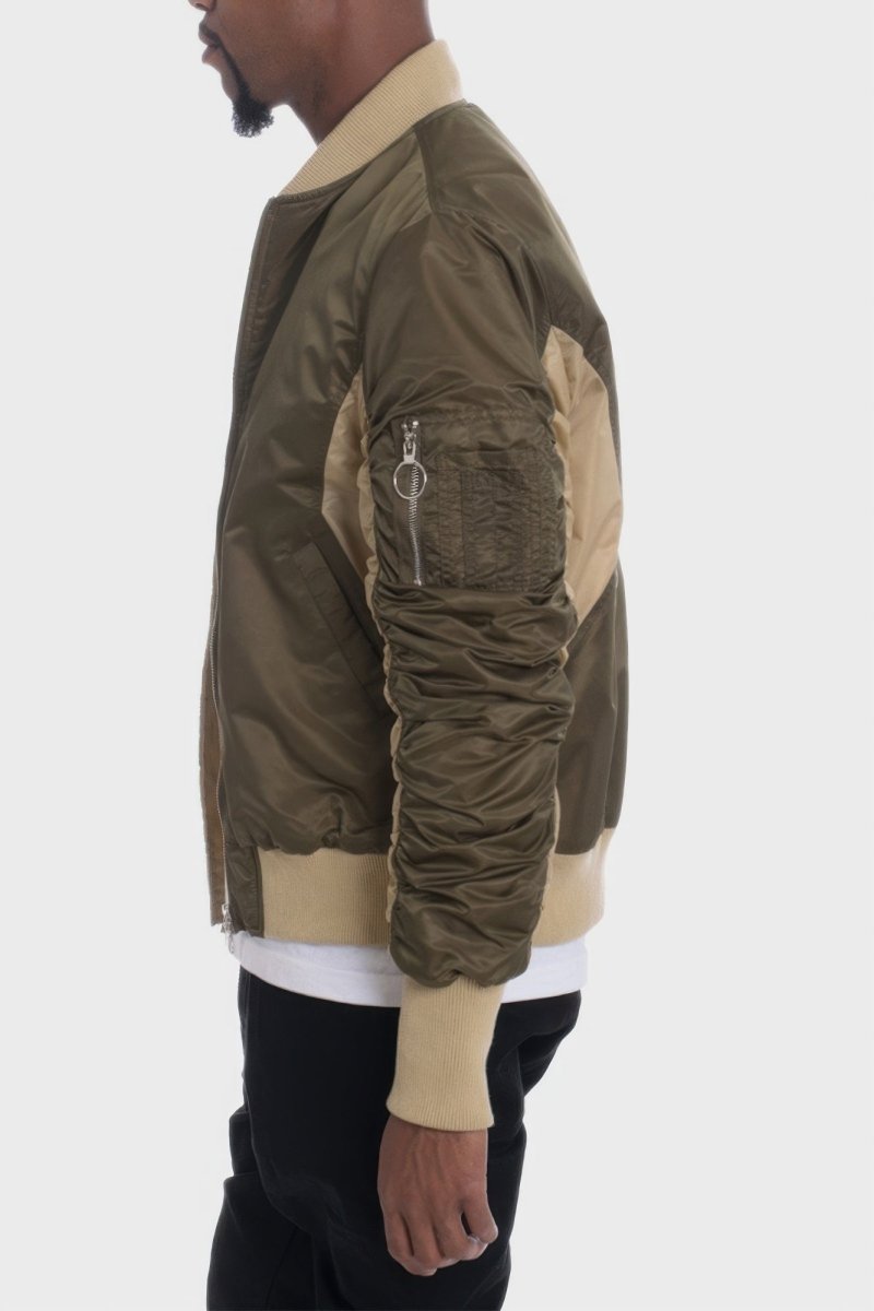 Person wearing a green and beige bomber jacket on a white background