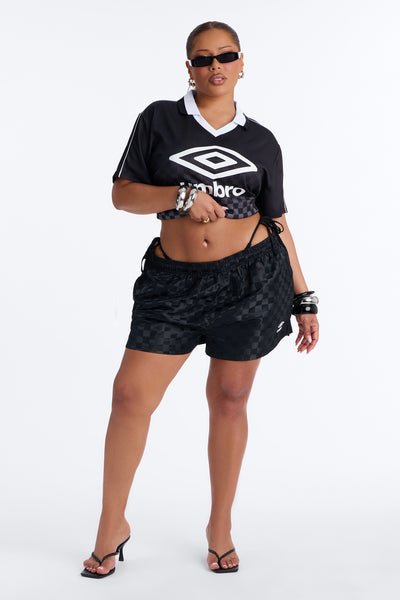 Woman wearing a black Umbro t-shirt and shorts on a white background
